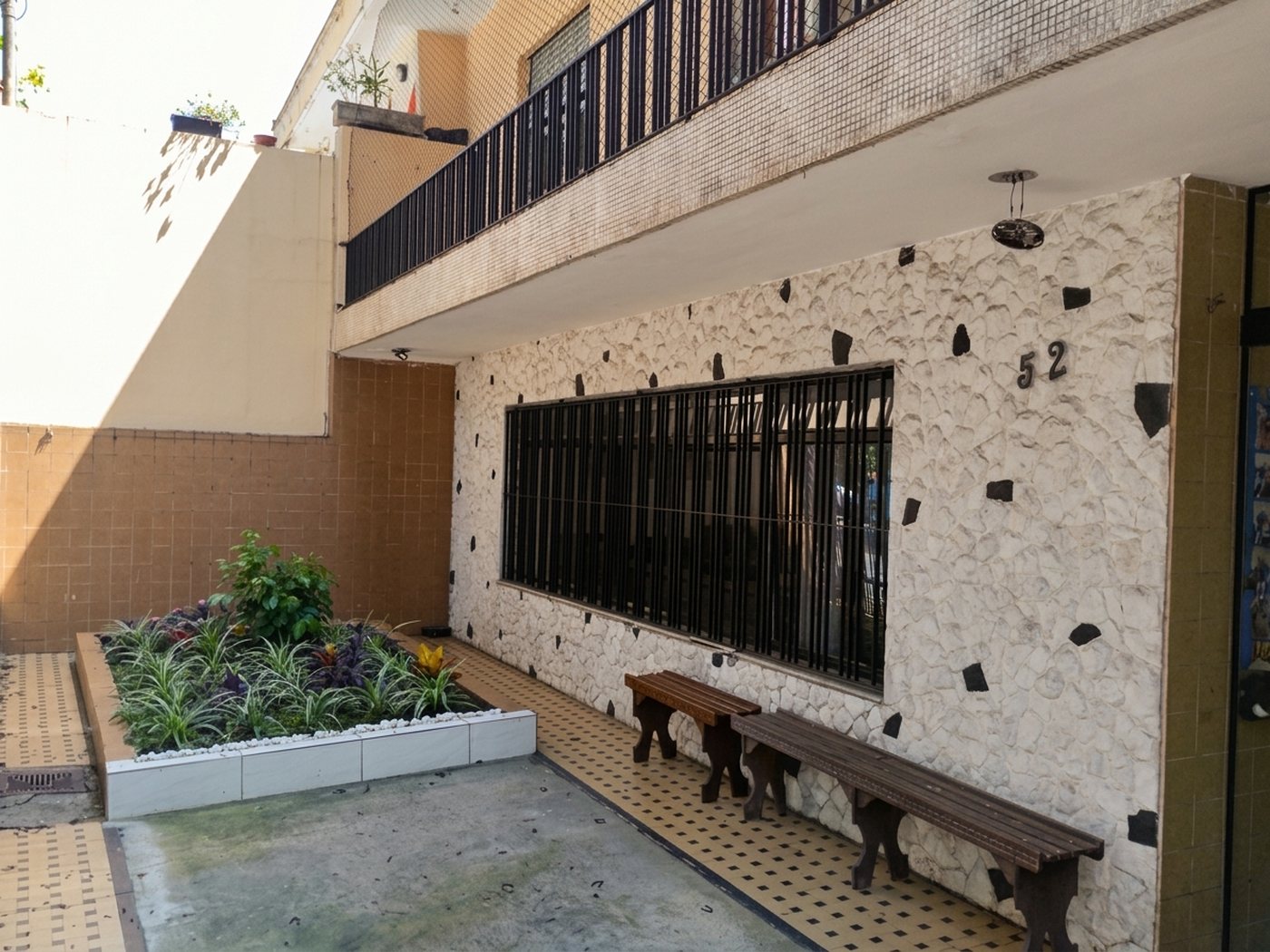 Pátio de entrada com canteiro e bancos de madeira